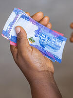Man's hand holding Tanzanian currency. Image: Imani Nsamila / UNU-WIDER